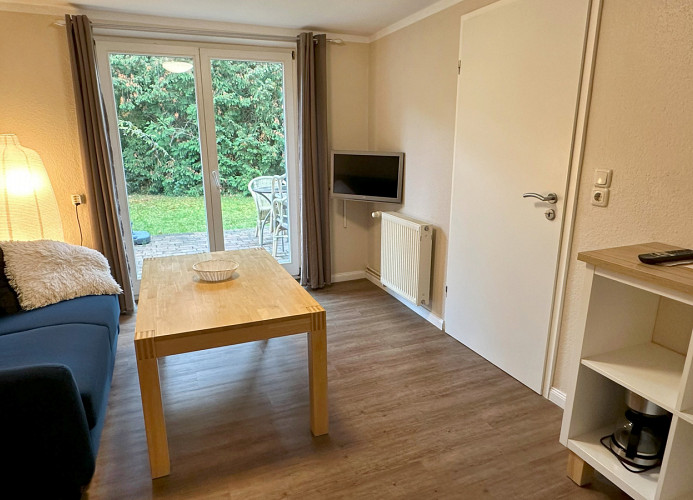 Wohnzimmer mit Couch, TV und Zugang zur eigenen Terrasse