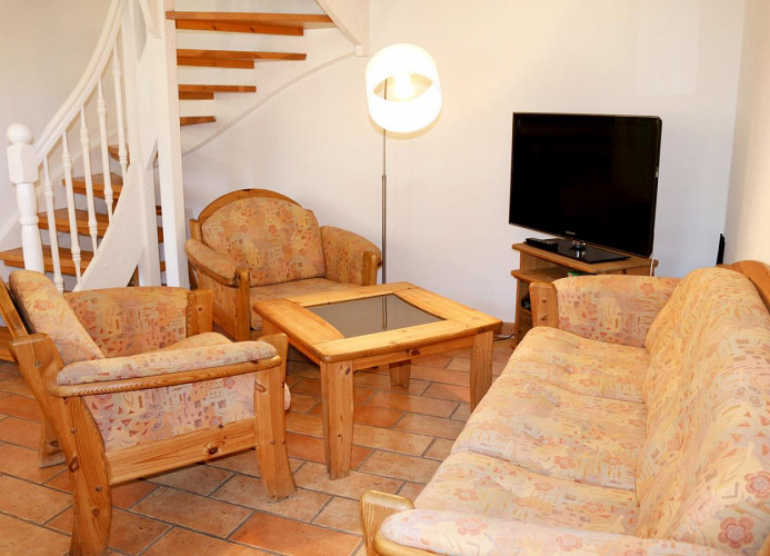 Sitzbereich im Wohnzimmer mit TV und Zugang zum Dachgeschoß