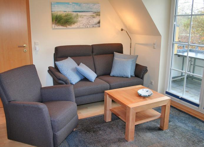 Wohnzimmer mit Couch, Sessel und Sat-TV