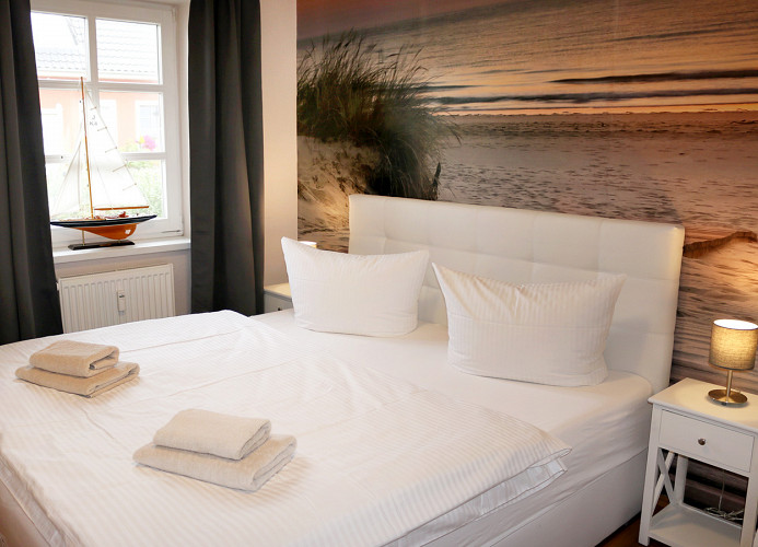 Schlafzimmer mit Doppelbett und Kleiderschrank (Kinderreisebettchen ist vorhanden), Insektenschutzgitter am Fenster