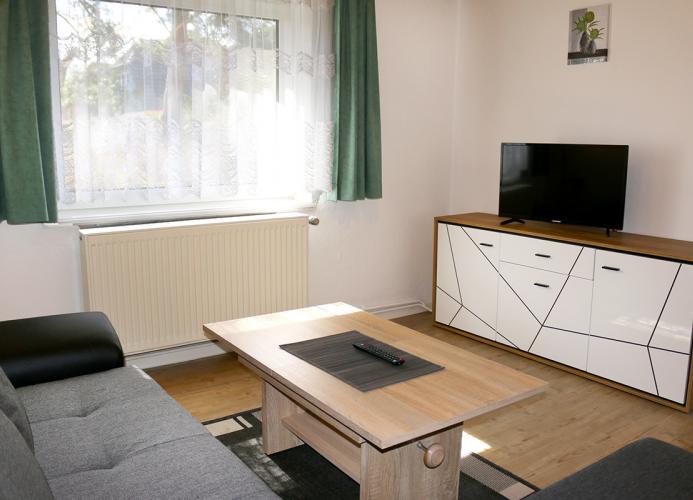 Wohnzimmer mit Eckcouch, Sessel und Sat-TV